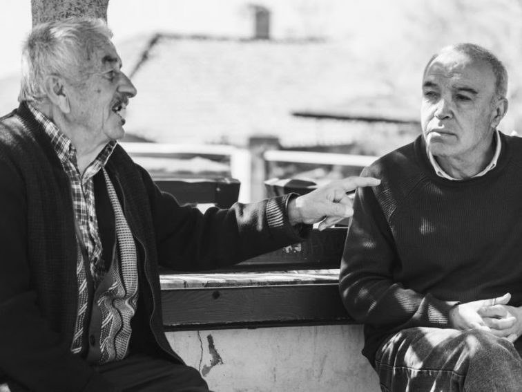 Two senior adults conversing outdoors, captured in black and white for a timeless feel.