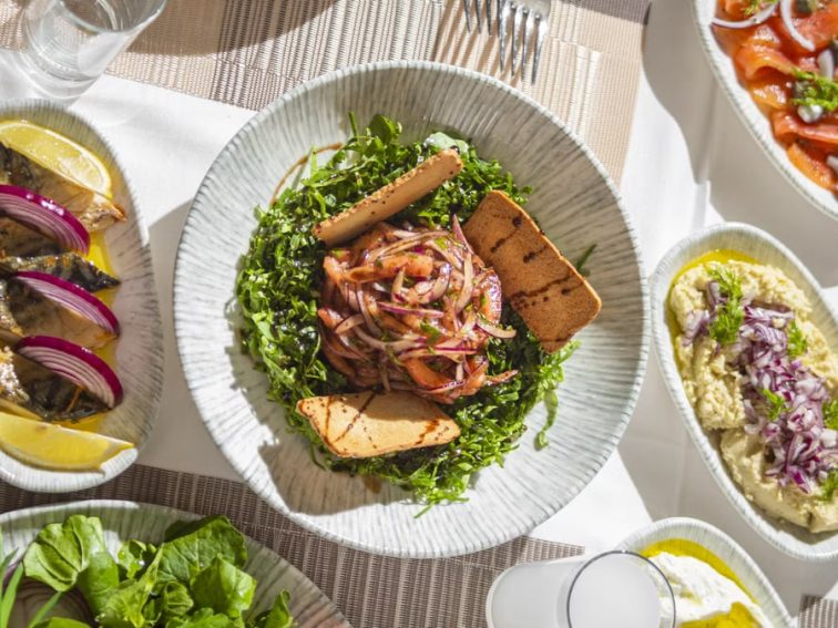 Top-down view of Mediterranean dishes including salads and seafood on an elegant table setting.